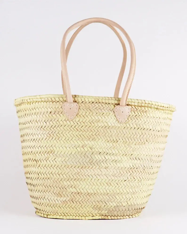 Woven straw tote bag with leather handles on a white background