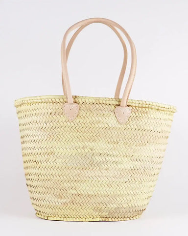 Woven straw tote bag with leather handles on a white background