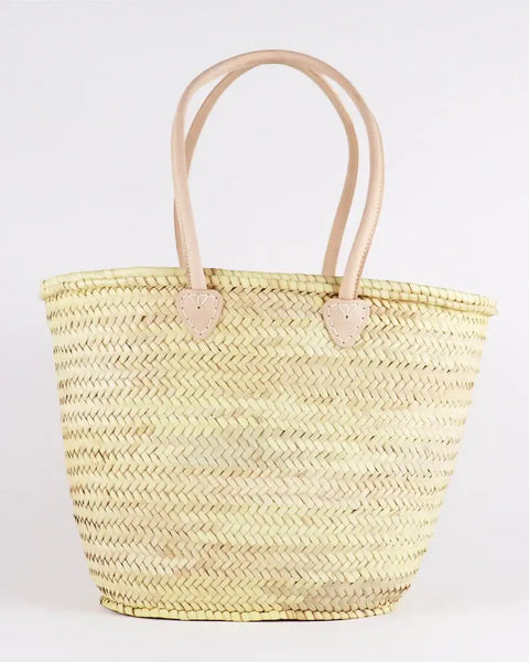 Woven straw tote bag with leather handles on a white background