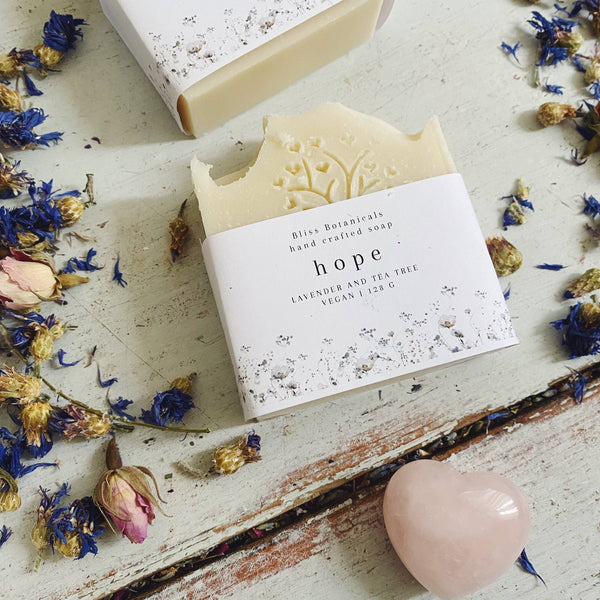 Handcrafted soap bar with 'hope' label surrounded by dried flowers on a rustic surface