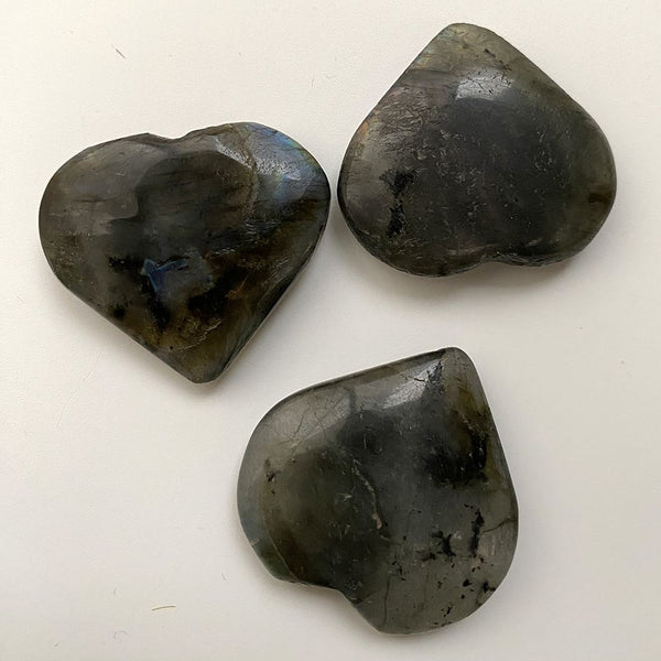 Three heart-shaped labradorite stones on a white background