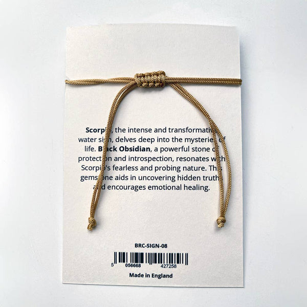 Gold threaded bracelet on a card with text about Scorpio and black obsidian