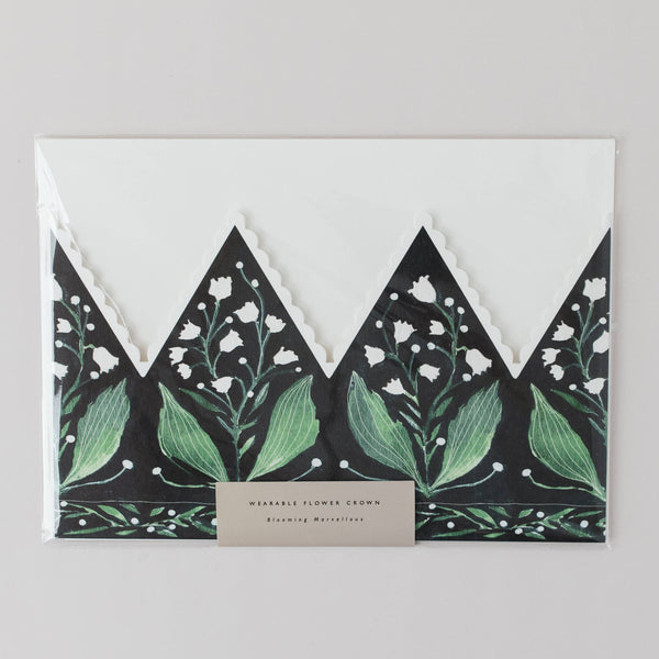Floral design crown greeting card with green leaves and white flowers on a black background, featuring a beige label.