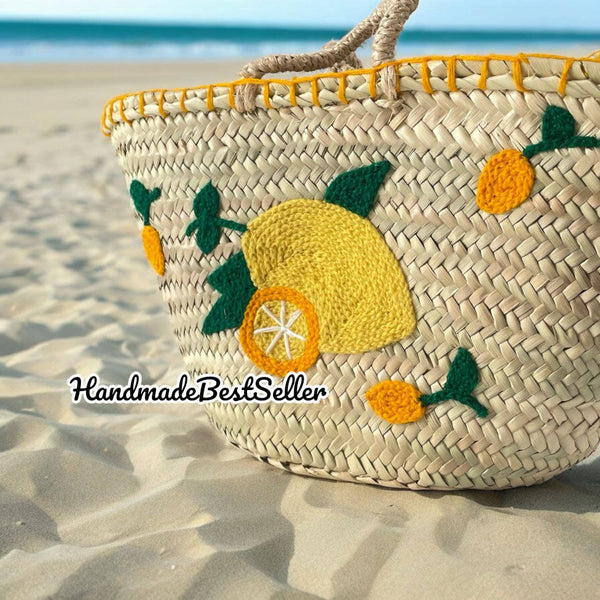 Woven basket with lemon and pineapple decorations on a sandy beach.