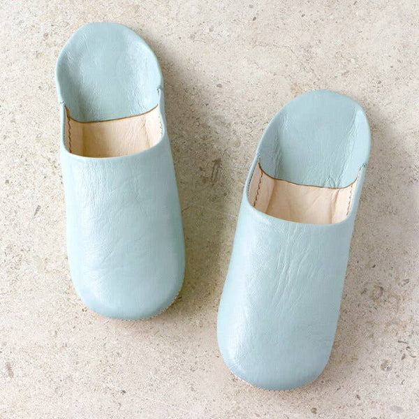 Pair of light blue slippers on a beige surface