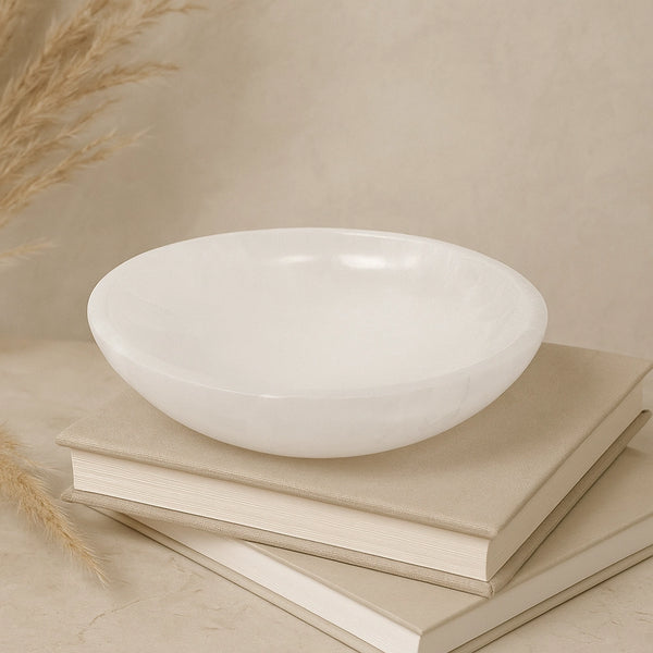 White crystal bowl on a stack of books with a neutral background