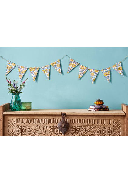 Decorative bunting with floral pattern hanging above a wooden console table against a light blue wall.