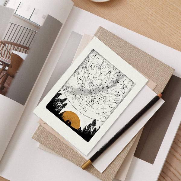 Greeting card with a black and white design on a table with a pen and notebook.