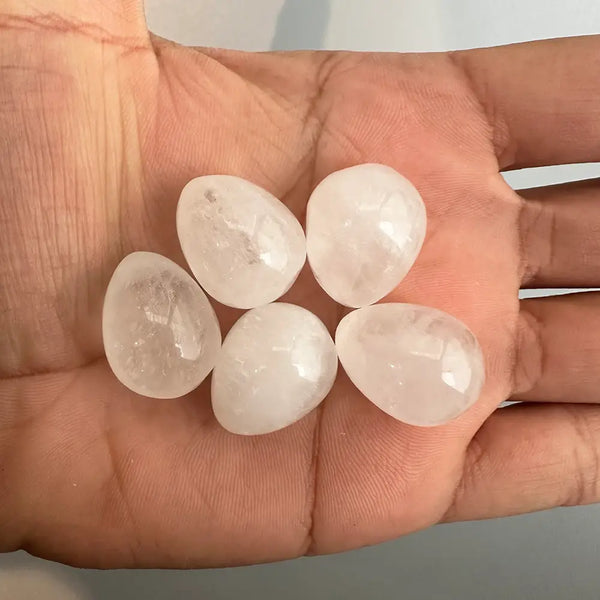 Five clear gemstones held in a hand against a neutral background