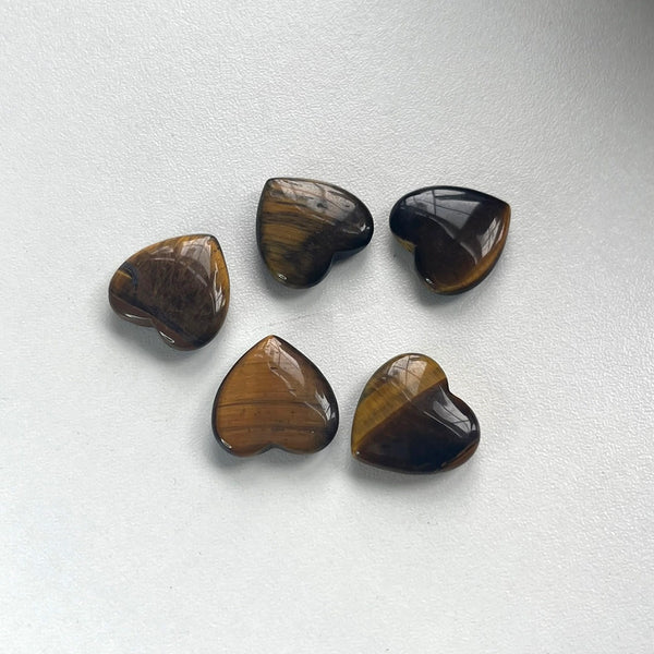Five heart-shaped tiger's eye stones on a white background