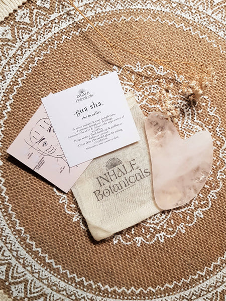 INHALE Botanicals gua sha board with a card on a textured surface