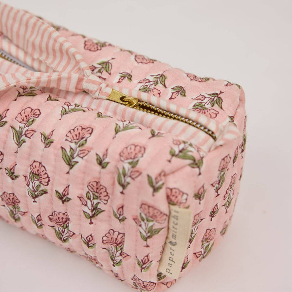 Pink floral fabric pouch with a gold zipper on a light background