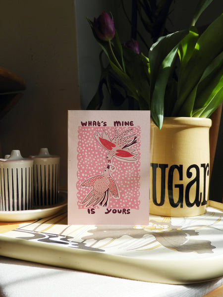 Card with pink design and text on a table with a 'Sugar' container and tulips in the background
