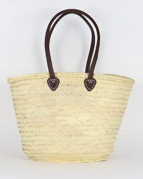 Woven straw bag with brown handles on a white background