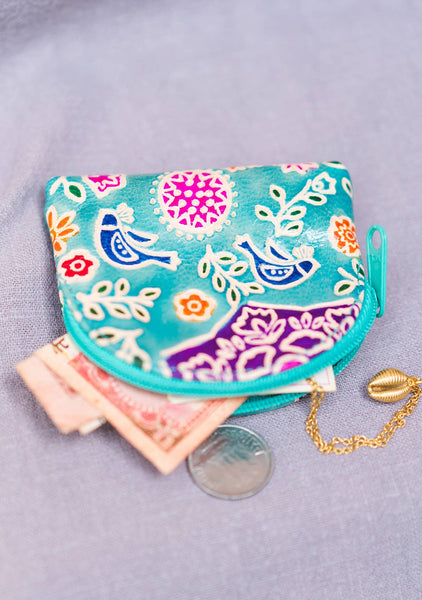 Colourful patterned coin purse with currency notes and a coin on a light purple background