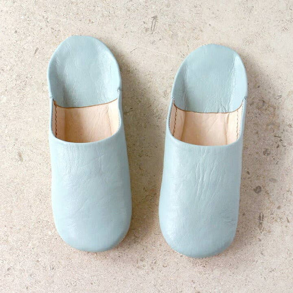 Pair of light blue slippers on a beige surface