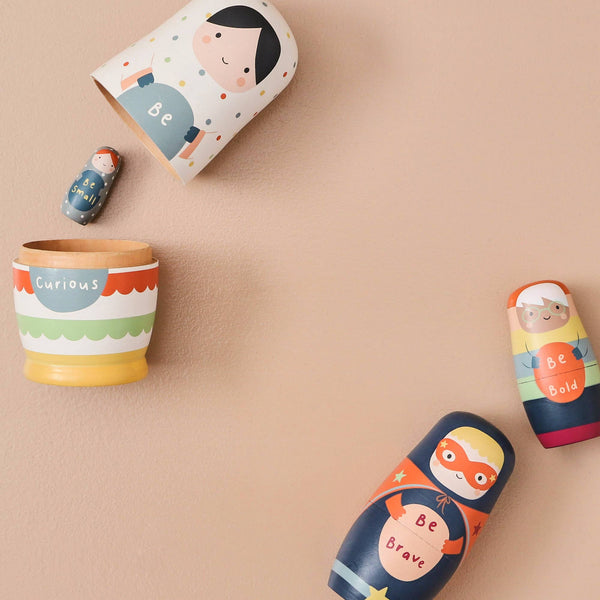 Set of colourful children's nesting dolls with motivational phrases on a beige background