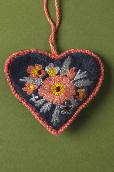 Heart-shaped embroidered decoration with floral patterns on a green background