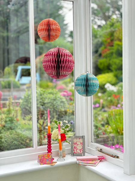 Decorative paper lanterns hanging by a window with garden view