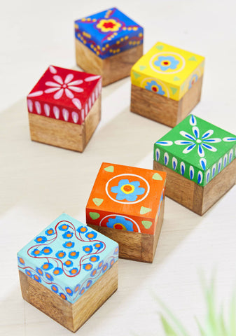 Set of colourful wooden boxes with floral patterned lids on a light background