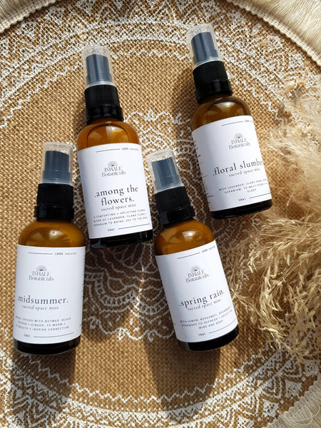 Four bottles of Inhale Botanicals space mist on a textured surface
