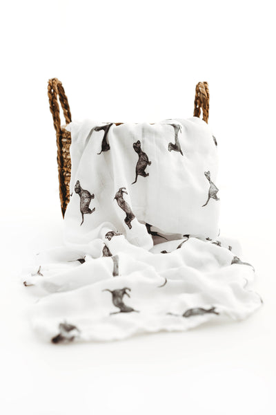 White fabric with dachshund pattern draped over a woven basket on a white background