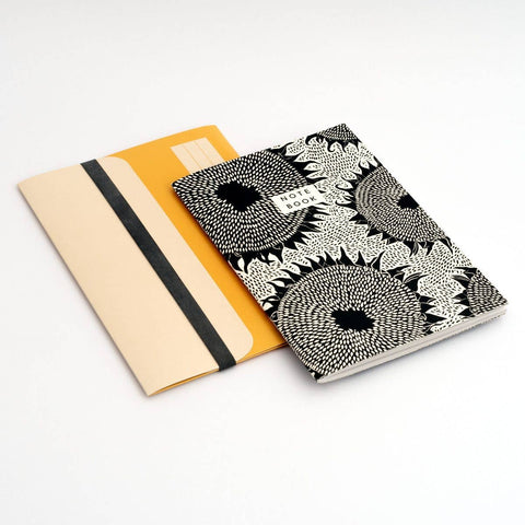 A notebook with a black and white floral pattern an d a folder on a white background