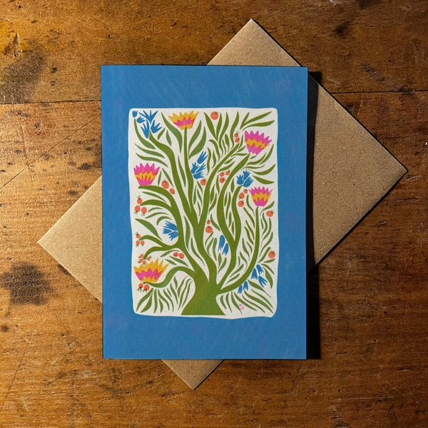 Greeting card with floral design on blue background and brown envelope on wooden surface