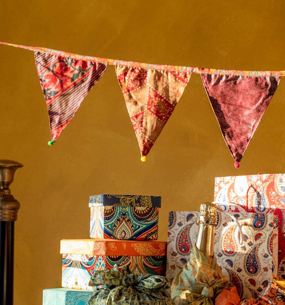 Decorative fabric bunting and patterned gift boxes against a yellow wall.