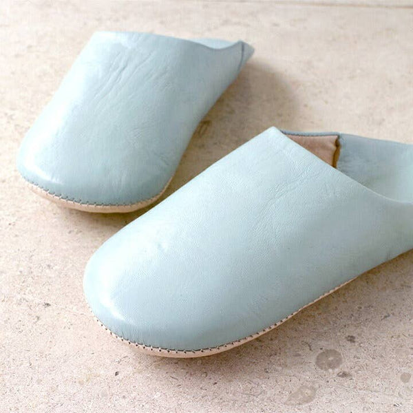 Pair of light blue slippers on a beige surface