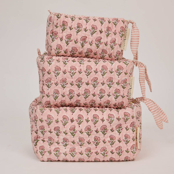 Set of three pink floral-patterned cosmetic bags stacked on a white background