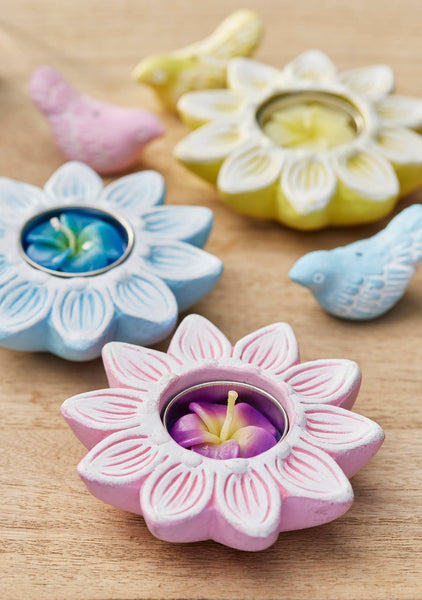 Flower-shaped candle holders with candles on a wooden surface
