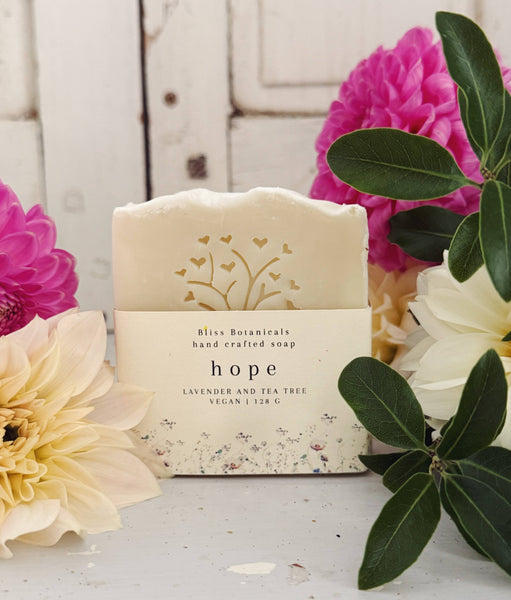 Handcrafted soap bar with a decorative label surrounded by flowers on a wooden surface