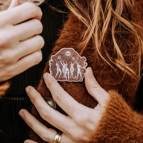 Person wearing a brown jacket with a decorative brooch on the chest.