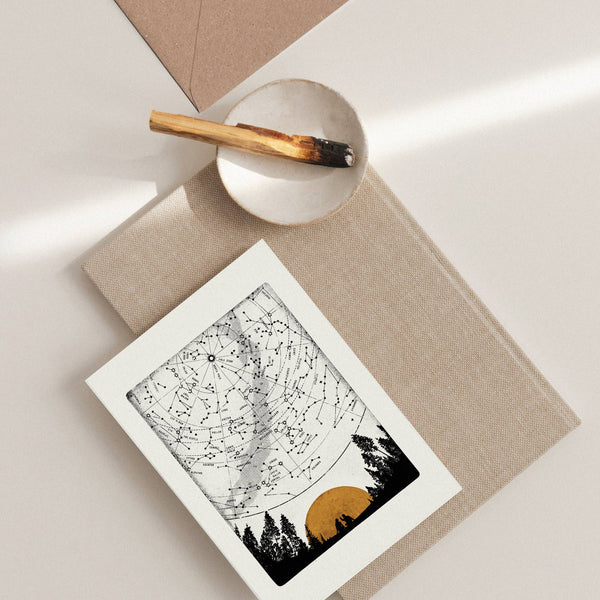 Greeting card of a star map on a textured surface with a pen and small bowl