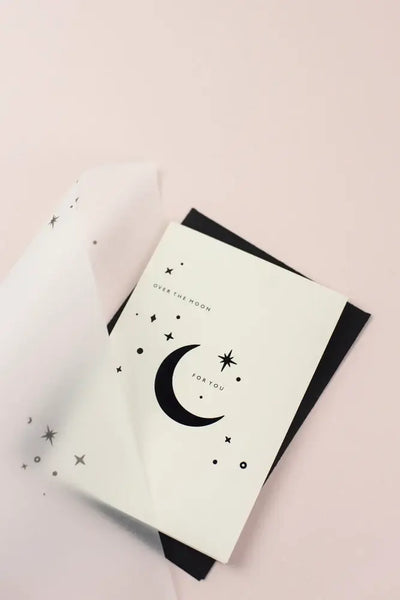 Greeting card with moon and star design on a pink background