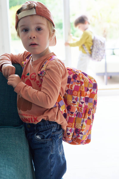 Child wearing a colourful backpack indoors