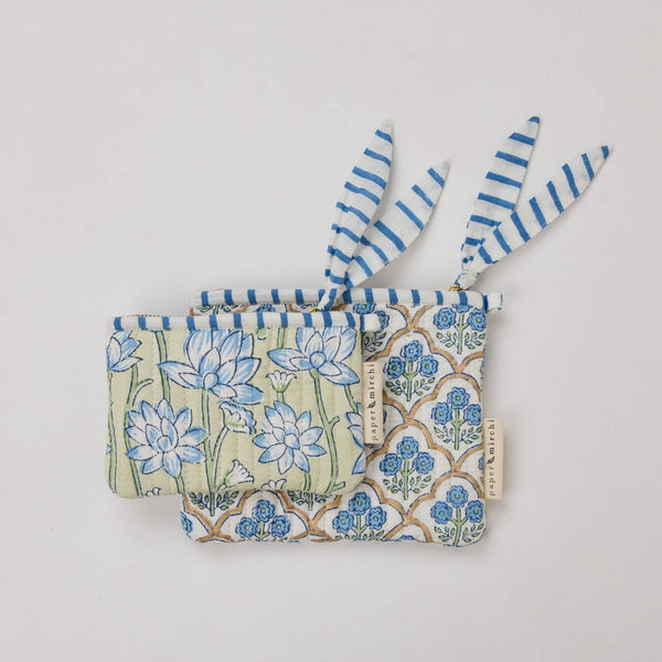 Fabric pouches with floral designs and striped trim on a light background