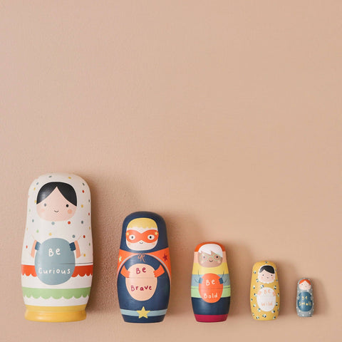 Set of colourful nesting dolls with motivational phrases on a beige background
