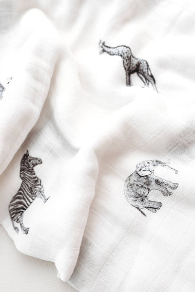 White fabric with black animal prints including zebras and elephants on a light background