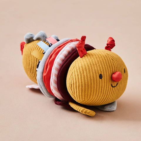 Yellow caterpillar-shaped plush toy with colorful segments on a beige background