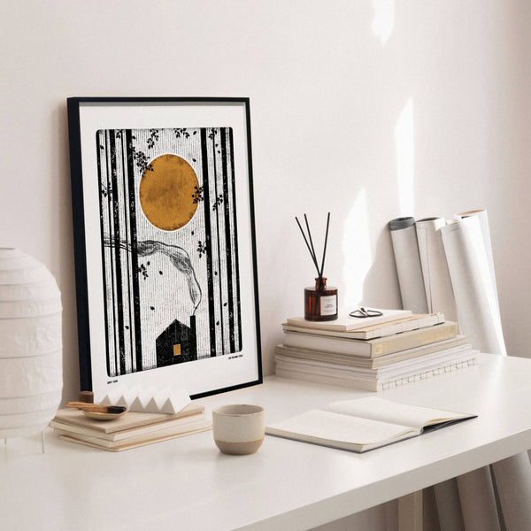 Framed artwork on a white desk with books and decor items.