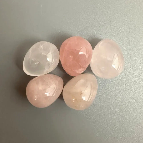 Five rose quartz stones on a grey background