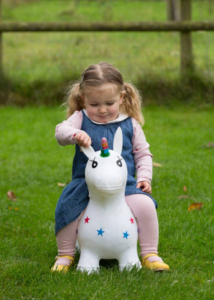 Child riding a unicorn hopper toy on grass