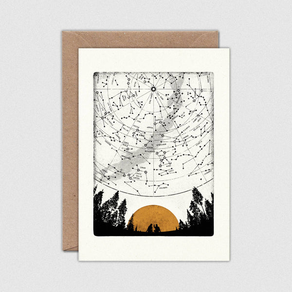 Greeting card with star map design featuring a sunset and trees, on a white background with a brown envelope.