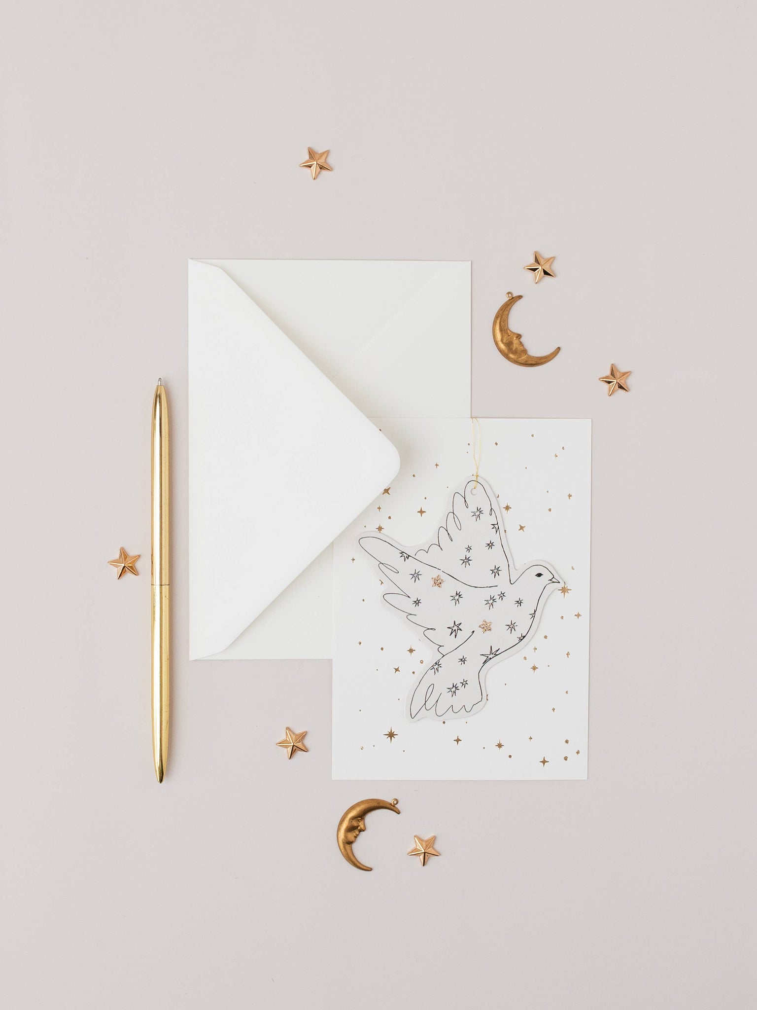 White card with a dove design, gold pen, and decorative elements on a light gray background