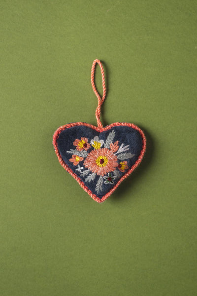 Embroidered heart-shaped ornament with floral design on a green background