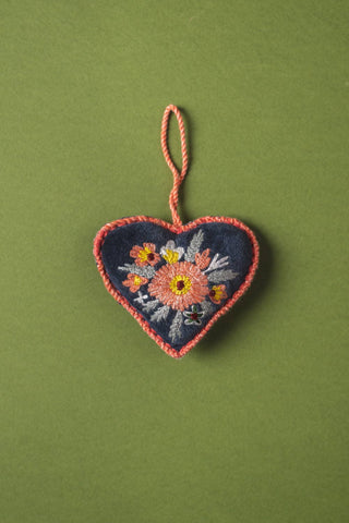 Embroidered heart-shaped ornament with floral design on a green background