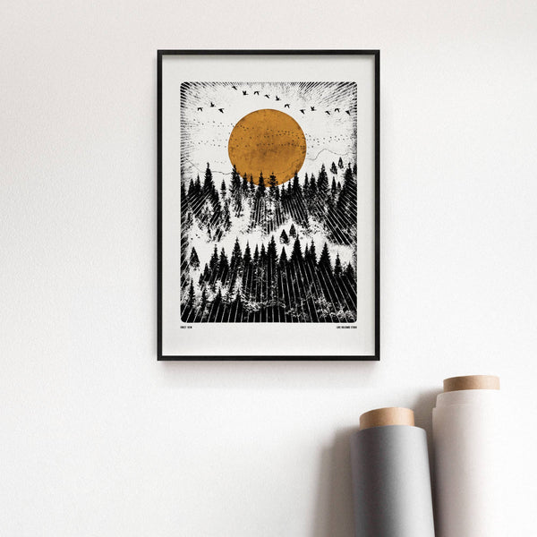 Framed artwork of a forest with a large orange moon on a white wall.