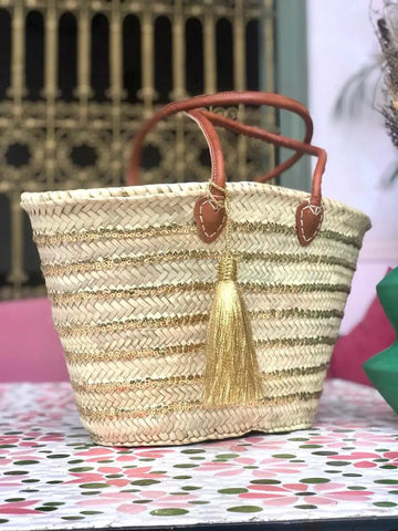 Woven straw bag with tassel on a floral tablecloth